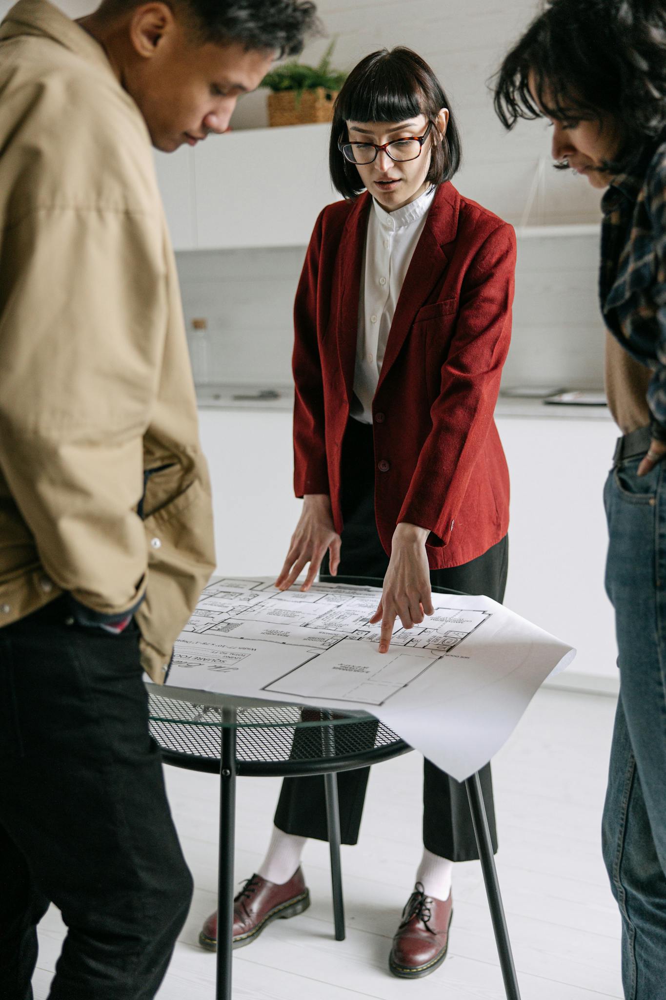 A real estate professional discusses architectural plans with clients in an office setting.